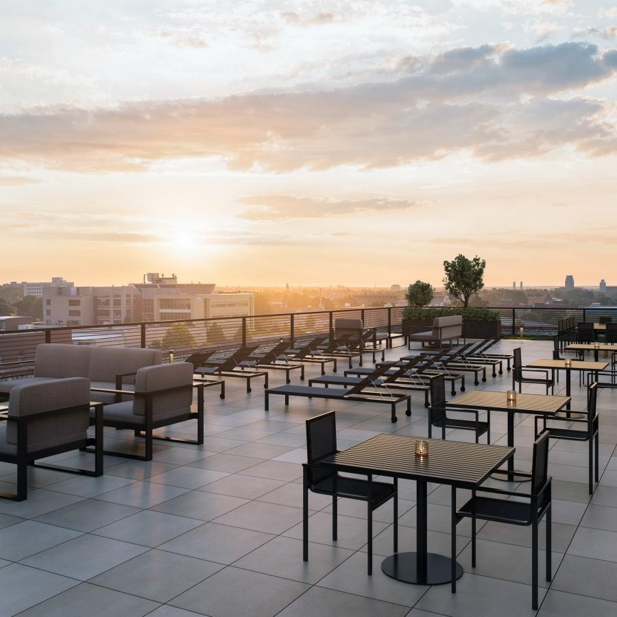 a rooftop patio with tables and chairs at dusk